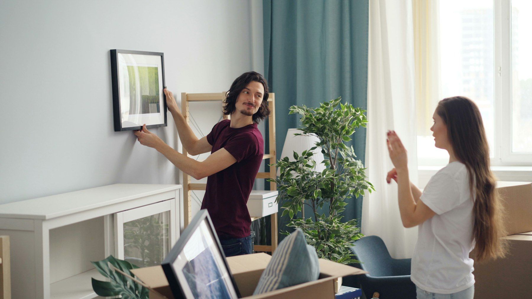 Couple hanging a framed picture in their new home