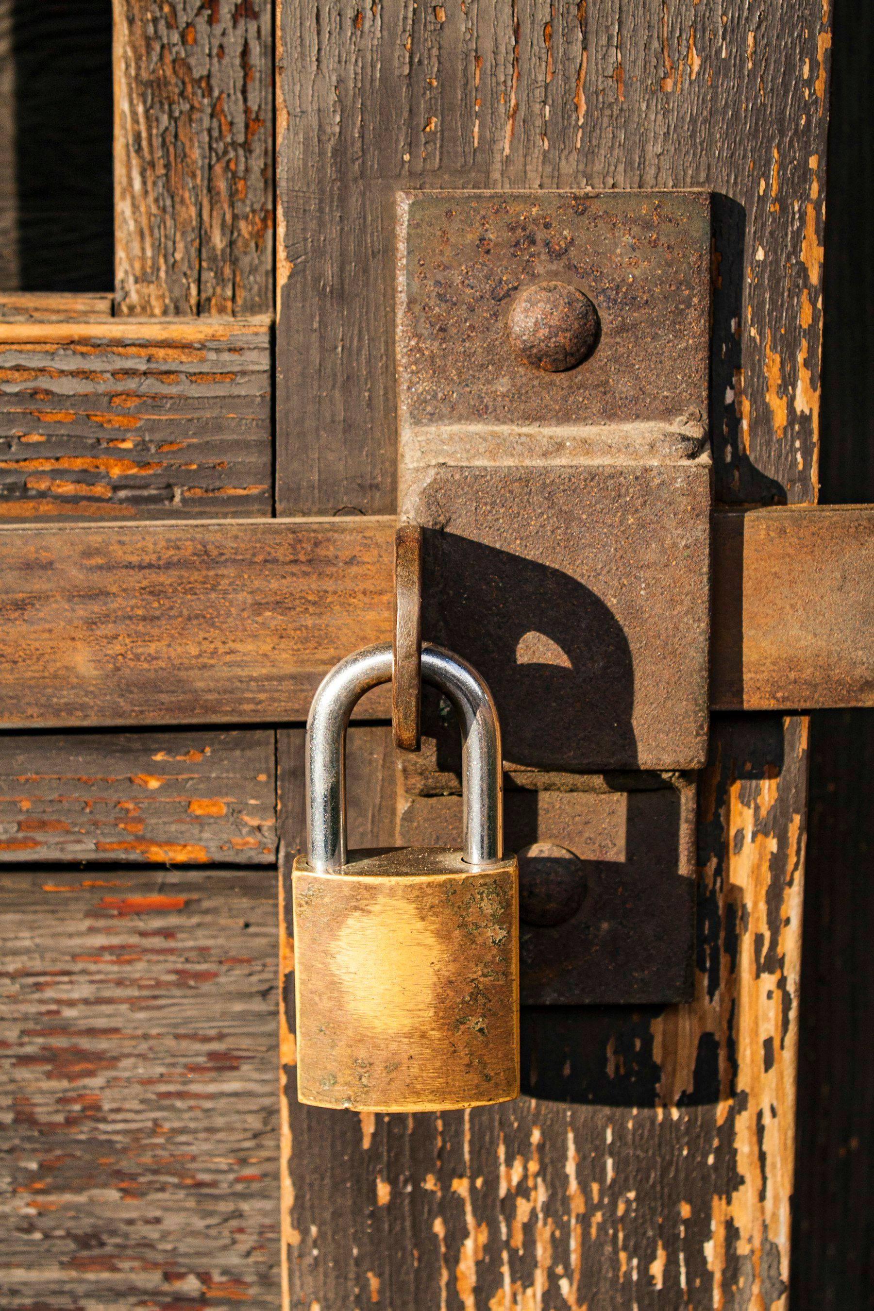 Brass padlock securing a wooden door