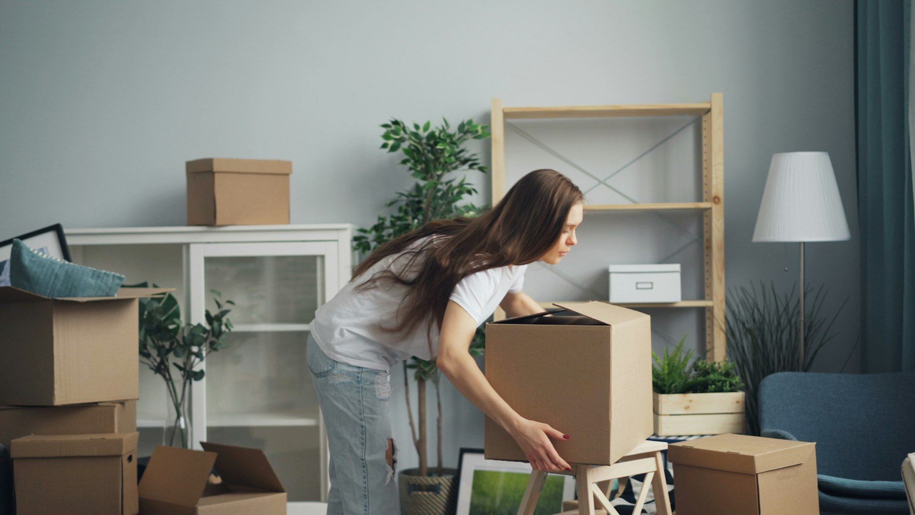Woman packing household items into a cardboard box